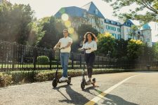 A man and a woman riding scooters down a street