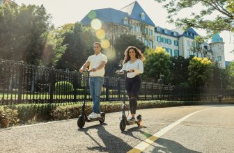A man and a woman riding scooters down a street